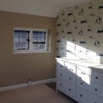 Bedroom with light coming through window and wallpaper with boats on