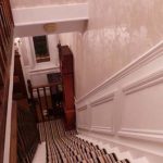 Image of hallway stairs with a striped carpet and grandfather clock